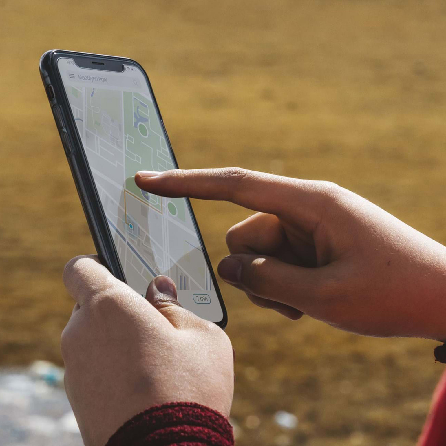 Hands holding a mobile phone which shows a map on its screen