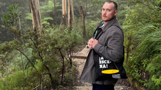 A man posing for a photo in a lush and green natural environment.