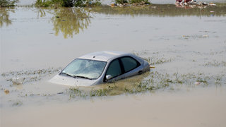 A grey car halfsunk stuck in water after a flood.