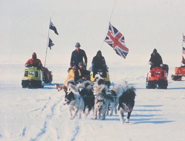 A group riding on skidoos carrying flags.