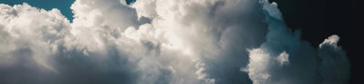 White fluffy clouds in a dark blue almost black sky. 