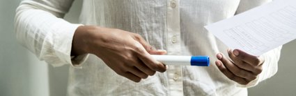 Close-up of a researcher holding a piece of paper and pen. 