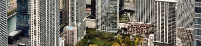 Cityscape with a park surrounded by high rise moder buildings. The buildings are lined by a sea. 