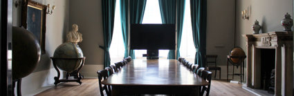 Stately looking meeting room with a large wooden table and several globes.