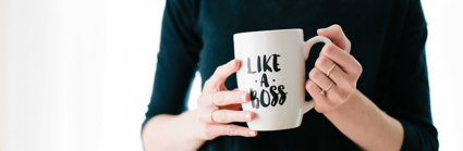 A person holding a mug that has 'like a boss' written on it.