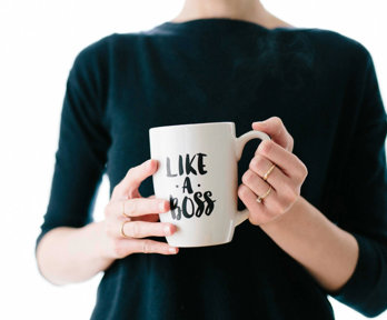 A person holding a mug that has 'like a boss' written on it.