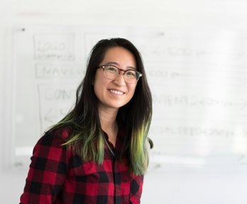 Woman standing in front of a white board, looking into the camera