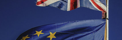 A Union Jack flag and the flag of the EU flying on a blue background