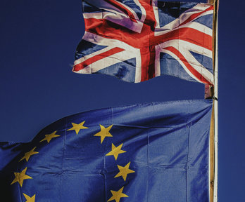 A Union Jack flag and the flag of the EU flying on a blue background