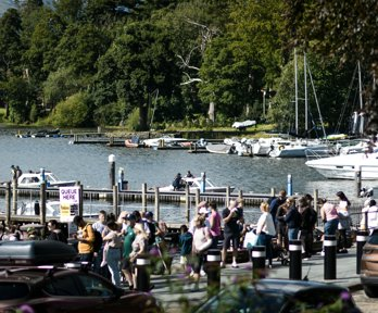 A view of Bowness with tourists and bpats on the lake