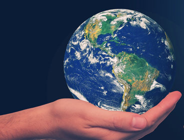 A hand holding a globe on a black background