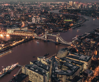 Aerial view of the City of London and Tower Bridge illuminated at night time.