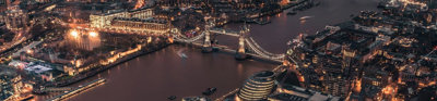 Aerial view of the City of London and Tower Bridge illuminated at night time.