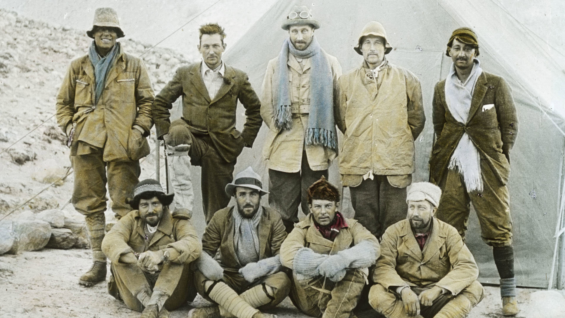 Old colour photo of members of the 1924 Mount Everest expedition posing for a group photo in camp in Tibet.