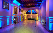 A drinks reception setup with blue, purple and yellow lighting.