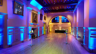 A drinks reception setup with blue, purple and yellow lighting.