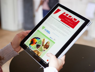 A person holding a tablet on which a page of the WIREs journal is showing.