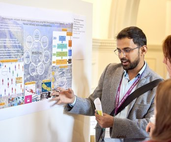 An man presenting his poster to conference delegates