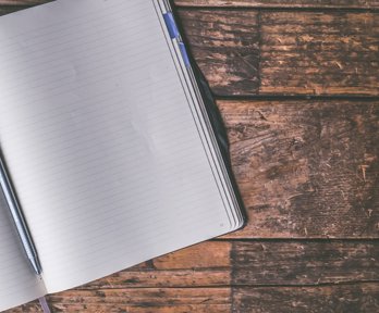 Open notebook and pen on a wooden table.