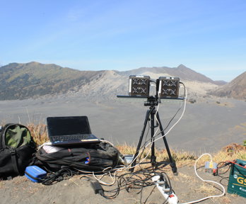 Laptop and UV monitoring equipment in mountainous landscape.