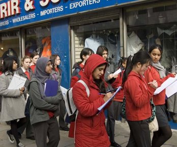 A group of female students with clipboards are walking down a high street taking notes of what they can see for their Geography fieldwork