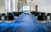 A meeting room setup in lecture theatre style with a screen at the front.