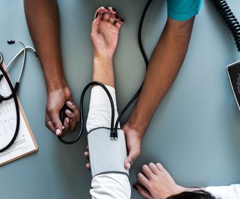 A medic holds a patients arm whilst a medical device is strapped around it