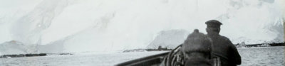 Old black and white photograph of two people in the front of a boat in Antarctica.