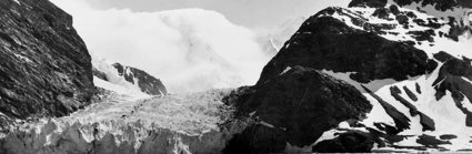 Black and white photograph showing a landscape with ice, snow and mountains.