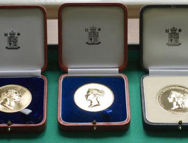 Three Society medals displayed in wooden boxes.