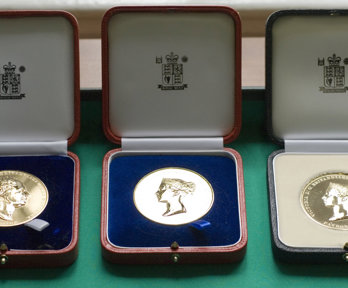 Three Society medals displayed in wooden boxes.