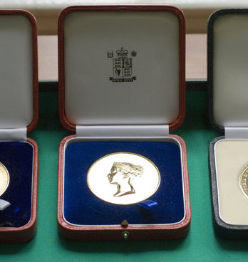 Three Society medals displayed in wooden boxes.