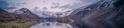 A lake in foreground surrounded by snow-capped mountains.