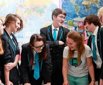 A geography ambassador laughing with a group of school pupils and showing them a map