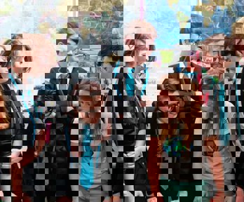 A geography ambassador laughing with a group of school pupils and showing them a map