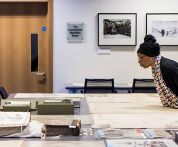 A woman looking at historic materials, including maps, books, and photographs