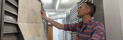 Person inspecting an old map in a vast map archive. 