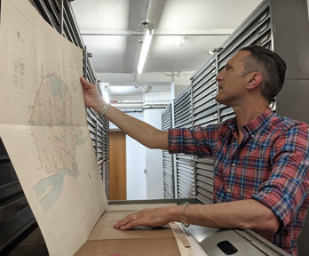 Person inspecting an old map in a vast map archive. 