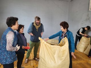 Four people standing around a large sack inspecting the agar-agar inside.