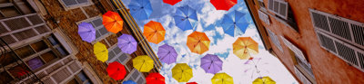 Colourful umbrellas hanging between buildings. 