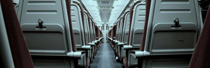 A view of a train aisle which splits rows of train seats in half 