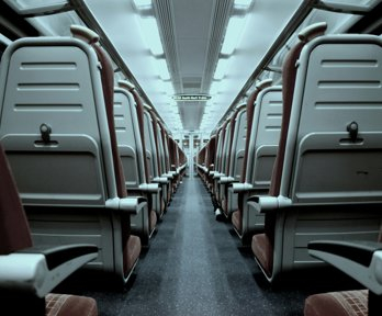 A view of a train aisle which splits rows of train seats in half 