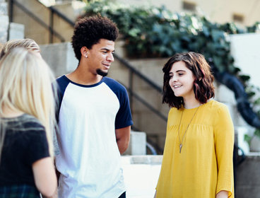 Three people talking outside in front of a set of stairs.