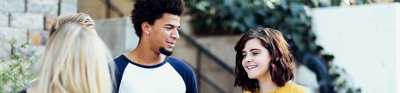 Three people talking outside in front of a set of stairs.