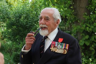 James Rawe holding a pipe and wearing several medals on his jacket