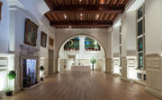 A grand hall at night with atmospheric white lighting and a catering table at the far end of the room.