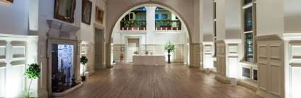 A grand hall at night with atmospheric white lighting and a catering table at the far end of the room.