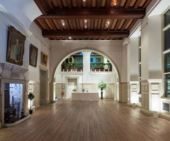 A grand hall at night with atmospheric white lighting and a catering table at the far end of the room.