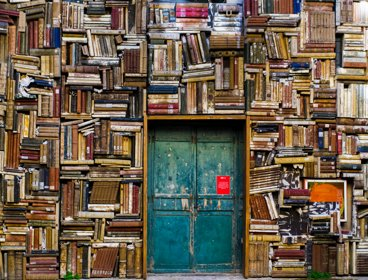 Huge piles of books surrounding an old blue door