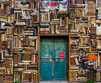 Huge piles of books surrounding an old blue door
